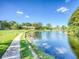 Peaceful pond-side walkway with lush landscaping at 7719 Cosme Dr # 1, Hudson, FL 34667