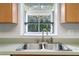 Stainless steel kitchen sink with wood cabinets and a window overlooking trees at 13080 Old Crystal River Rd, Brooksville, FL 34601