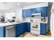 Kitchen with blue cabinets, white appliances, and tile floor at 13242 Little Farms Dr, Spring Hill, FL 34609