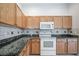 Well-equipped kitchen featuring wood cabinets, granite countertops, and modern appliances at 20743 Nectarine Pl, Land O Lakes, FL 34637