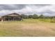 View of a golf cart storage shed on a community golf course with a grass fairway and cloudy skies at 2293 Dog Leg Ct, Brooksville, FL 34604