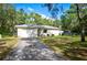 Single-story house with a white exterior and a long driveway at 9043 Glenarm Way, Weeki Wachee, FL 34613