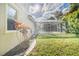 Enclosed backyard pool with landscaping featuring tropical plants, lush lawn, and a partial home view at 10441 Garda Dr, Trinity, FL 34655