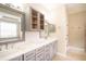 Bright bathroom with double sink vanity, marble countertops, decorative mirrors, and glass door cabinets at 10441 Garda Dr, Trinity, FL 34655