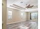Bright bedroom featuring wood-look floors, a recessed ceiling with a ceiling fan, and natural light from the windows at 10441 Garda Dr, Trinity, FL 34655