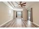 Spacious bedroom with a tray ceiling, ceiling fan, wood-look flooring, and a glass door with access to the yard at 10441 Garda Dr, Trinity, FL 34655