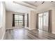 Large bedroom with wood floors, recessed ceiling, ceiling fan, windows with curtains, and glass door to patio at 10441 Garda Dr, Trinity, FL 34655