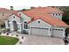 Beautiful two-story home featuring a three-car garage, red tile roof, and manicured landscaping at 10441 Garda Dr, Trinity, FL 34655