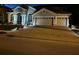 Exterior front elevation view of a beautiful house with three-car garage, paver driveway, and manicured landscaping at night at 10441 Garda Dr, Trinity, FL 34655