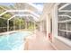 Enclosed pool area with brick-paved deck and a partial view of the lush yard and trees at 10441 Garda Dr, Trinity, FL 34655