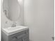 Small bathroom with gray vanity, round mirror, and white sink at 10693 Calluna Dr, Odessa, FL 33556