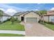 Tan house with gray garage door and landscaping; a paved driveway leads to the home at 10693 Calluna Dr, Odessa, FL 33556