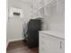 Laundry room with dark wood-look floors, white cabinets, and dark gray washer and dryer at 10693 Calluna Dr, Odessa, FL 33556