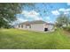 Tan house exterior with large grassy backyard and partial view of pool at 3527 Conifer Loop, Spring Hill, FL 34609