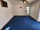 Empty room with blue carpet, ceiling fan, and natural light, offering a blank canvas for customization at 12266 Birch St, Brooksville, FL 34613