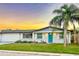 Charming ranch house with teal door and sunset at 3452 Umber Rd, Holiday, FL 34691