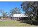 Large backyard featuring lush grass, various sheds and mature trees, with an inviting ambiance at 8700 Ross Ln, New Port Richey, FL 34654