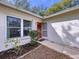 Front entrance with red door, screen door and well-maintained landscaping at 11015 Rollingwood Dr, Port Richey, FL 34668