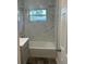 Updated bathroom with a bathtub, gray vanity, and marble-look tile at 7142 Carlow St, New Port Richey, FL 34653