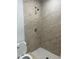 Modern shower with beige tile and a white toilet at 7142 Carlow St, New Port Richey, FL 34653