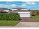 Two-story house with white exterior, two-car garage, and landscaping at 13022 Payton St, Odessa, FL 33556