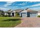 Two-story home with gray exterior, three car garage, and a brick driveway at 19907 Tattnall Way, Brooksville, FL 34601