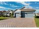 Two-story home with gray exterior, three car garage, and a brick driveway at 19907 Tattnall Way, Brooksville, FL 34601