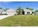 House exterior with beige siding, attached two-car garage, green lawn, and palm tree at 2468 Magellan Ave, Spring Hill, FL 34608