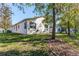 Back exterior view of the house with a large tree and green grass at 11544 Mcleod St, Spring Hill, FL 34609