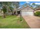 Gray house with white garage door, landscaping, and a palm tree in the front yard at 7347 Sugarbush Dr, Spring Hill, FL 34606