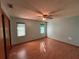 A simple bedroom featuring a ceiling fan, windows with blinds, and light hardwood flooring at 1000 Godfrey Ave, Spring Hill, FL 34609