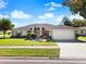 Single-story home with a two-car garage and landscaped lawn at 10464 Henderson St, Spring Hill, FL 34608