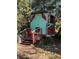 Charming playhouse with red and teal paint, wooden stairs, and a fenced area at 12520 Hicks Rd, Hudson, FL 34669