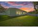 Home's backyard at sunset, showcasing the patio and lawn at 12739 Balsam Ave, Hudson, FL 34669
