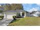 House exterior featuring a green facade, two-car garage, and landscaped lawn at 12739 Balsam Ave, Hudson, FL 34669