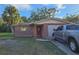 Brick ranch house with red door, attached garage, and a truck parked in the driveway at 8030 Gulf Way, Hudson, FL 34667