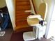 Tan stair lift chair installed on wooden stairs at 13730 Gene Rossi Ave, Hudson, FL 34667