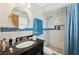 Modern bathroom with a granite countertop, framed mirror, and marble tiled walk-in shower at 7941 Sycamore Dr, New Port Richey, FL 34654