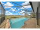 Backyard view of the pool inside screened enclosure overlooking green pasture under a blue sky at 24005 Frederick Dr, Brooksville, FL 34601