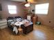 Bedroom featuring two windows, ceiling fan, hardwood floors, and a traditional wooden chest at 11187 Blythville Rd, Spring Hill, FL 34608