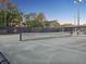 View of an outdoor tennis court with a shaded viewing area and perimeter fencing for a suburban community at 121 Lindsay Ln # 31, Oldsmar, FL 34677