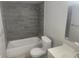 Updated bathroom with gray tile and a new bathtub at 12804 Waterbury Ave, Hudson, FL 34669