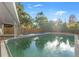 A backyard pool surrounded by a wooden fence and trees under a sunny sky at 4939 18Th St, Zephyrhills, FL 33542
