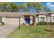 Tan brick home with a blue front door, nicely landscaped lawn, and a snowman decoration at 7423 Woodhollow Rd, Spring Hill, FL 34606