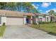 Tan brick home with attached garage, landscaped lawn, and a snowman decoration at 7423 Woodhollow Rd, Spring Hill, FL 34606