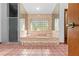 Pink bathroom with large tub, glass block window, and tiled floor at 7443 Oak Tree Ln, Spring Hill, FL 34607