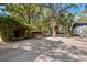 Expansive driveway with two rustic carports surrounded by lush greenery and mature trees at 7600 138Th St, Seminole, FL 33776
