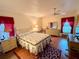 Bright bedroom with stylish furniture, red window treatments, fan, desk, and warm lighting at 8704 Winding Wood Dr, Port Richey, FL 34668