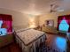 Cozy bedroom featuring a comfortable bed, warm lighting, ceiling fan and red accents at 8704 Winding Wood Dr, Port Richey, FL 34668