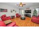 Comfortable living room with a ceiling fan, wood flooring, and plush red seating for a cozy entertainment area at 11645 Belle Haven Dr, New Port Richey, FL 34654